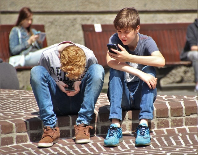 children sitting on curb cellphones